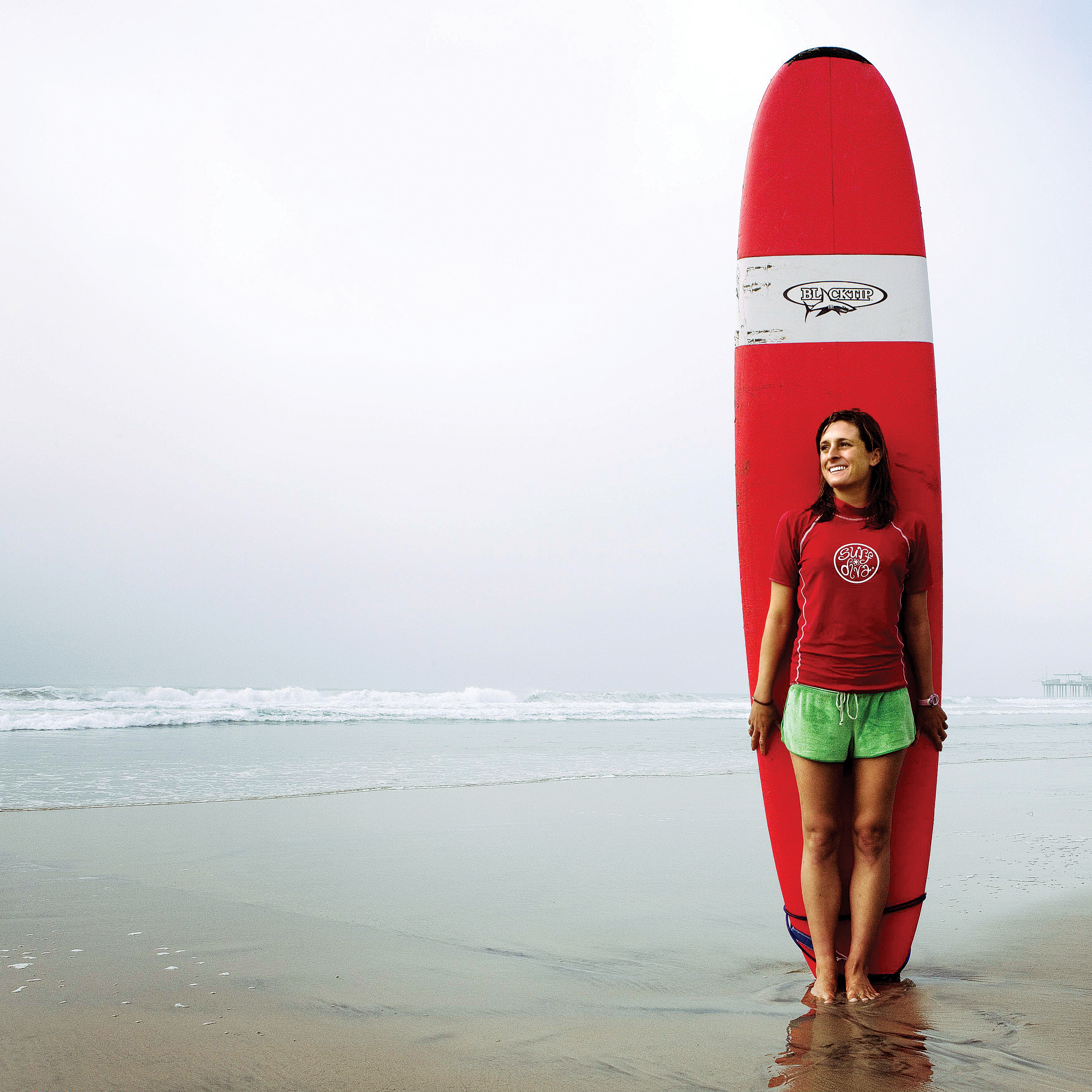 Woman standing with longboard on the beach in one of the best places to live in the West