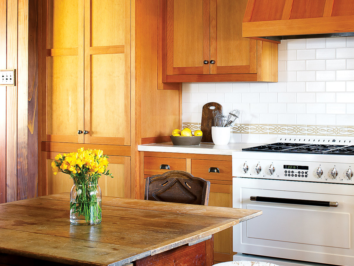 a bright, orange, modern kitchen island  with a steel countertop sits in the middle of this updated, vintage style kitchen