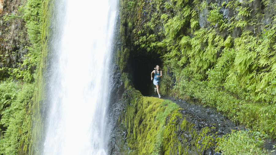 Woman running under Devils Falls on the Northern Three Sisters Wilderness area of the PCT