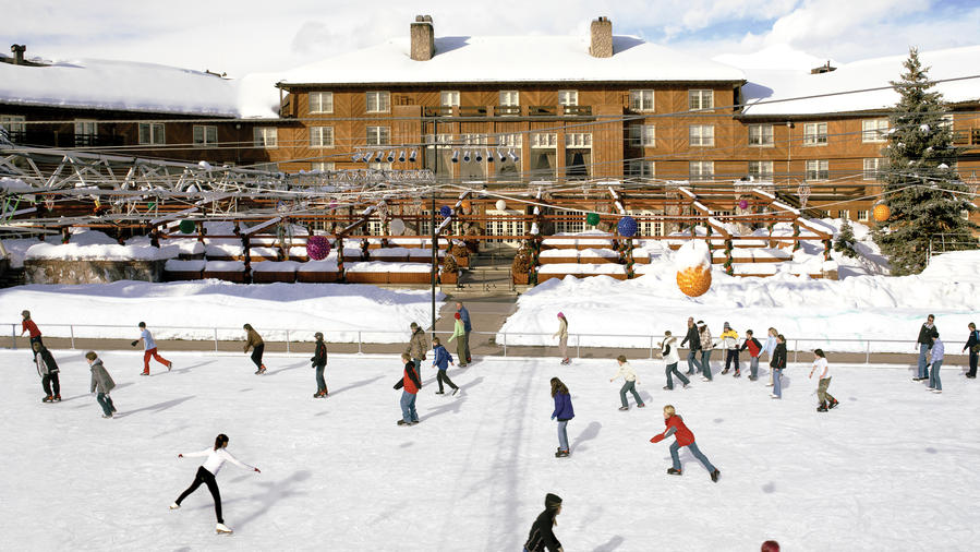 People ice skating in front of the snow-covered Sun Valley Lodge in Idaho